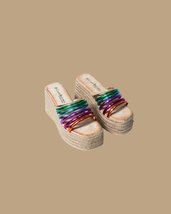 Siente la brisa del verano con nuestras Alpargatas Altea, una explosión de color, altura y comodidad. Su plataforma de esparto natural estiliza sin esfuerzo, mientras las tiras multicolor añaden ese toque divertido y moderno que transforma cualquier look. Perfectas para tus días de sol, escapadas o simplemente para brillar donde vayas. Con diseño artesanal y alma alegre, la Altea no es una alpargata más... es tu nuevo imprescindible.