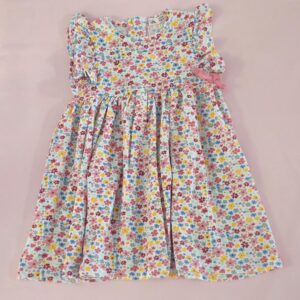 Vestido de niña con estampado floral multicolor y lazo rosa, ideal para verano, moda infantil española.