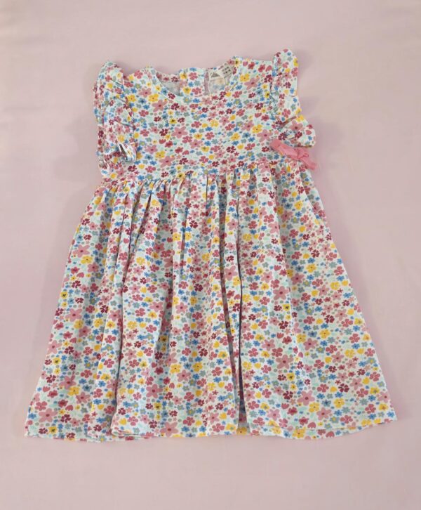 Vestido de niña con estampado floral multicolor y lazo rosa, ideal para verano, moda infantil española.