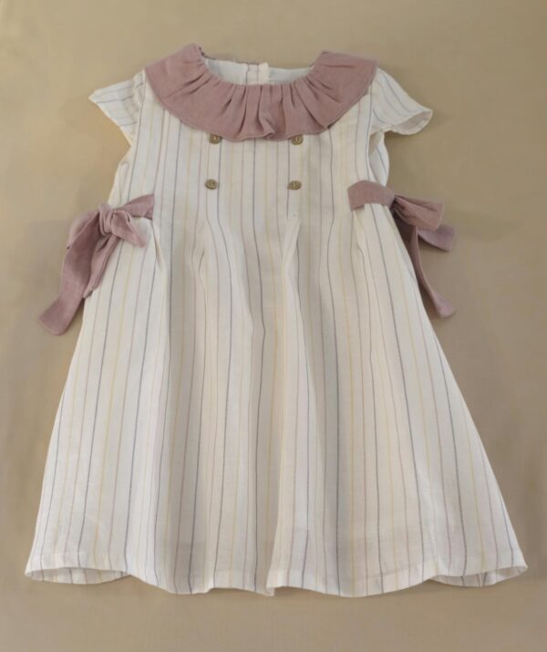 Vestido infantil de rayas crudo con cuello rosa y lazos a los lados.